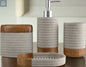 Close up view of gray and wood bathroom accessories set including soap dispenser, tumbler, toothbrush holder, and soap dish