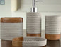 Close up view of gray and wood bathroom accessories set including soap dispenser, tumbler, toothbrush holder, and soap dish