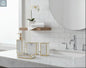 White marble bathroom accessories set with gold trim including soap dispenser, toothbrush holder, tumbler, and soap dish