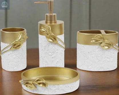 White and gold bathroom accessories set with leaf detail including soap dispenser, toothbrush holder, tumbler, and soap dish