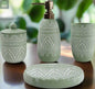 Green patterned bathroom accessories set with soap dispenser, toothbrush holder, tumbler, and soap dish on countertop