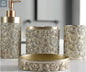 Gold ornate patterned bathroom accessories set with soap dispenser, toothbrush holder, tumbler, and soap dish on countertop