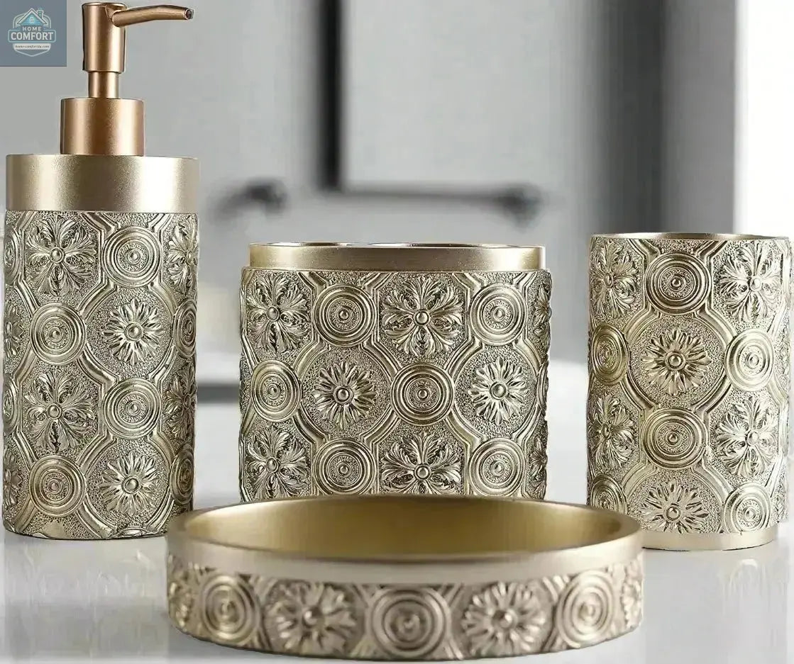Gold ornate patterned bathroom accessories set with soap dispenser, toothbrush holder, tumbler, and soap dish on countertop