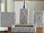 Gray textured stone bathroom accessories set with soap dispenser, toothbrush holder, tumbler, and soap dish on countertop