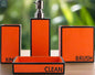 Orange modern bathroom accessories set with soap dispenser, toothbrush holder, tumbler, and soap dish labeled rinse brush and clean