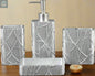 Silver textured bathroom accessories set with soap dispenser, toothbrush holder, tumbler, and soap dish with abstract pattern on countertop