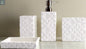 White geometric textured bathroom accessories set with soap dispenser, toothbrush holder, tumbler, and soap dish on countertop