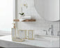 White marble bathroom accessories set with gold trim including soap dispenser, toothbrush holder, tumbler, and soap dish