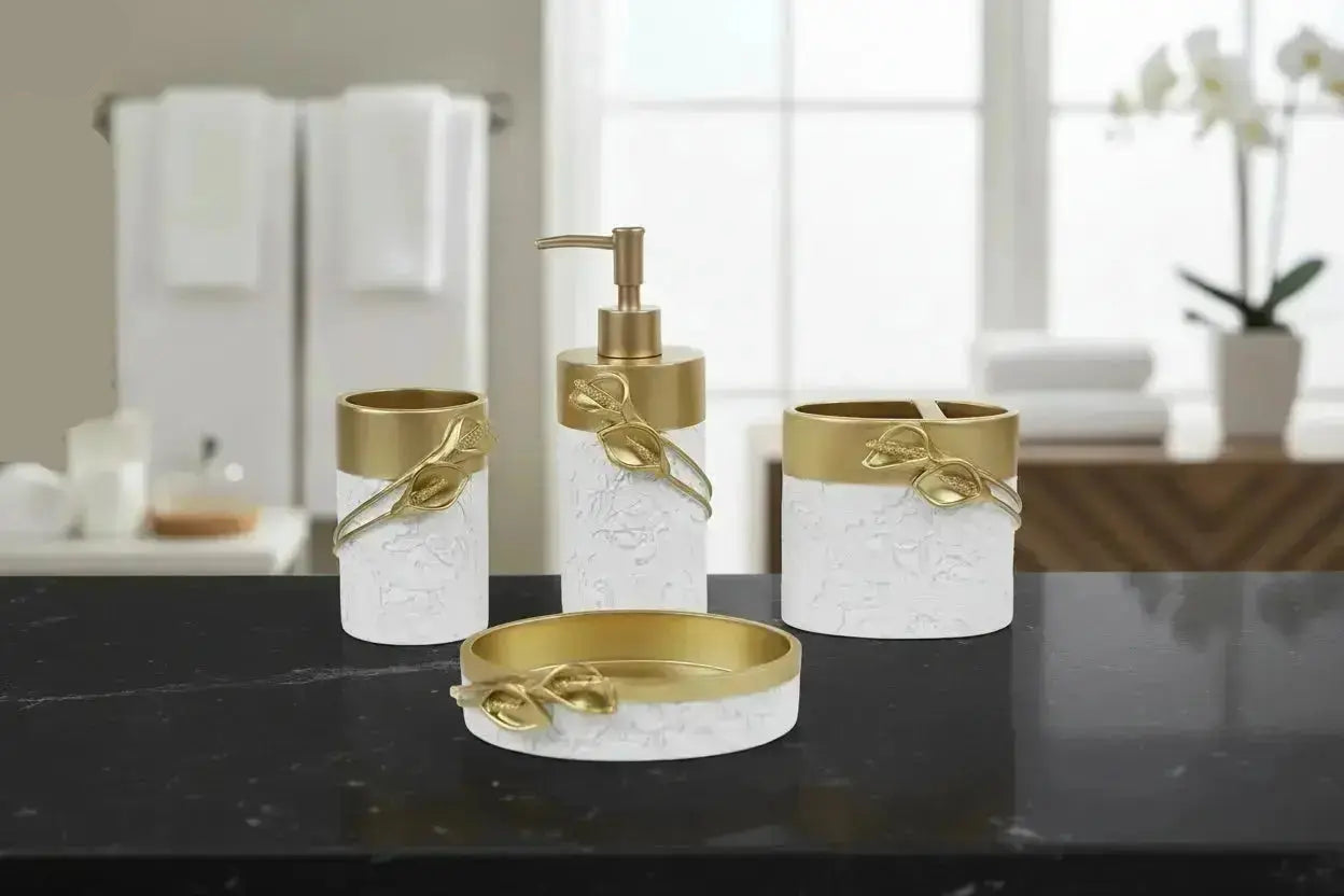 White and gold bathroom accessories set with leaf detail including soap dispenser, toothbrush holder, tumbler, and soap dish