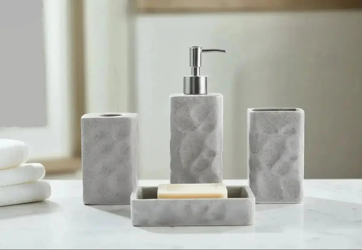 Gray textured stone bathroom accessories set with soap dispenser, toothbrush holder, tumbler, and soap dish on countertop