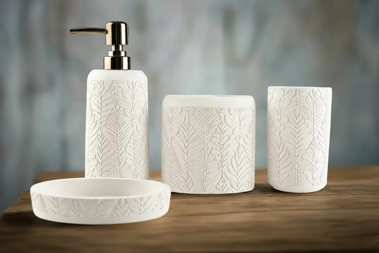 White embossed leaf pattern bathroom accessories set with soap dispenser, toothbrush holder, tumbler, and soap dish on countertop