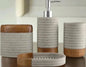 Close up view of gray and wood bathroom accessories set including soap dispenser, tumbler, toothbrush holder, and soap dish