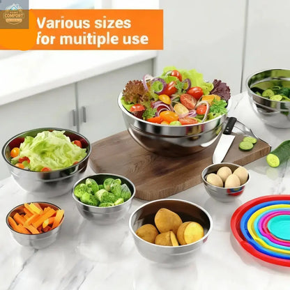 Stainless steel mixing bowls with lids used for food preparation including salad vegetables and ingredients on kitchen counter
