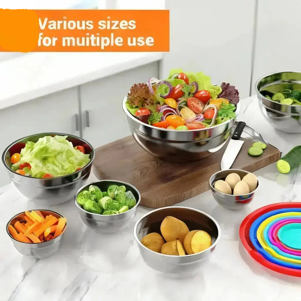 Stainless steel mixing bowls with lids used for food preparation including salad vegetables and ingredients on kitchen counter
