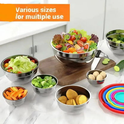 Stainless steel mixing bowls with lids used for food preparation including salad vegetables and ingredients on kitchen counter

