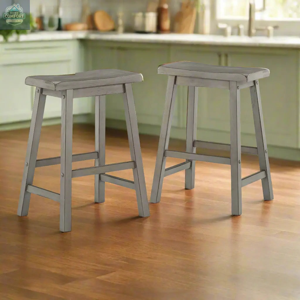 Set of two grey wood backless counter stools with saddle seats shown in kitchen setting