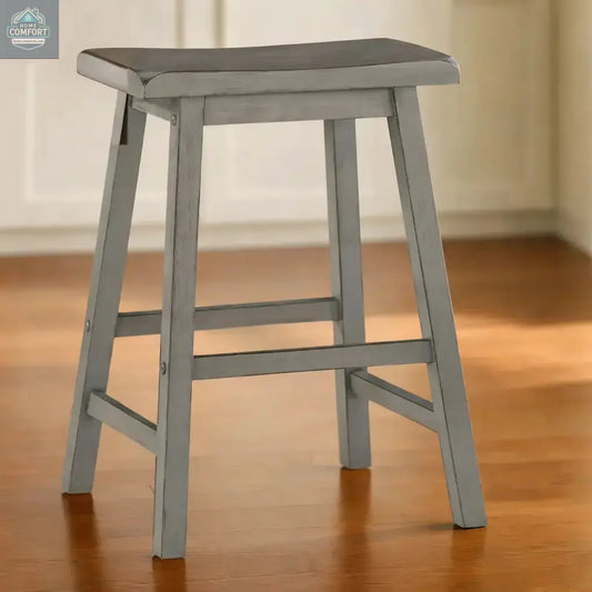 Single grey wood backless counter stool with saddle seat shown on indoor floor