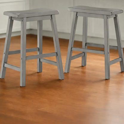 Set of two grey wood backless counter stools with saddle seats shown in kitchen setting