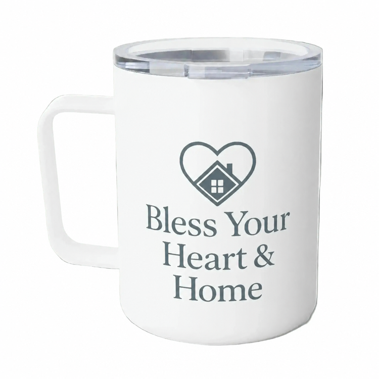 A white insulated mug with a clear lid, featuring a dark gray heart-shaped house icon and the text 'Bless Your Heart & Home' printed on the front.