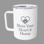 A white insulated travel mug with a clear lid, featuring a dark gray heart-shaped house graphic and the text 'Bless Your Heart & Home' printed on the front.