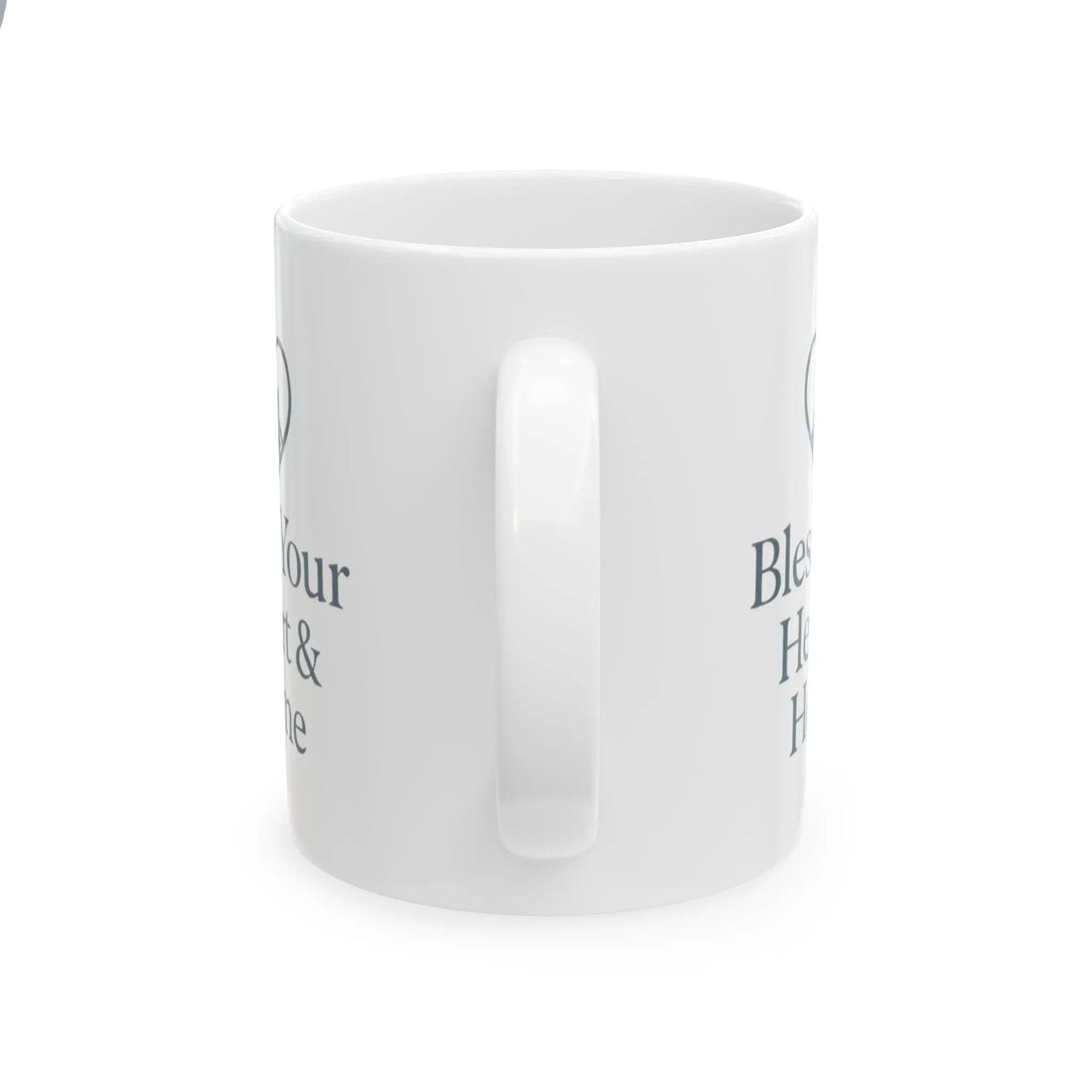 A white ceramic mug with a glossy finish, shown from a side angle on a white background. The mug features dark gray text partially visible on both sides, including the words 'Bless' and 'Home'.