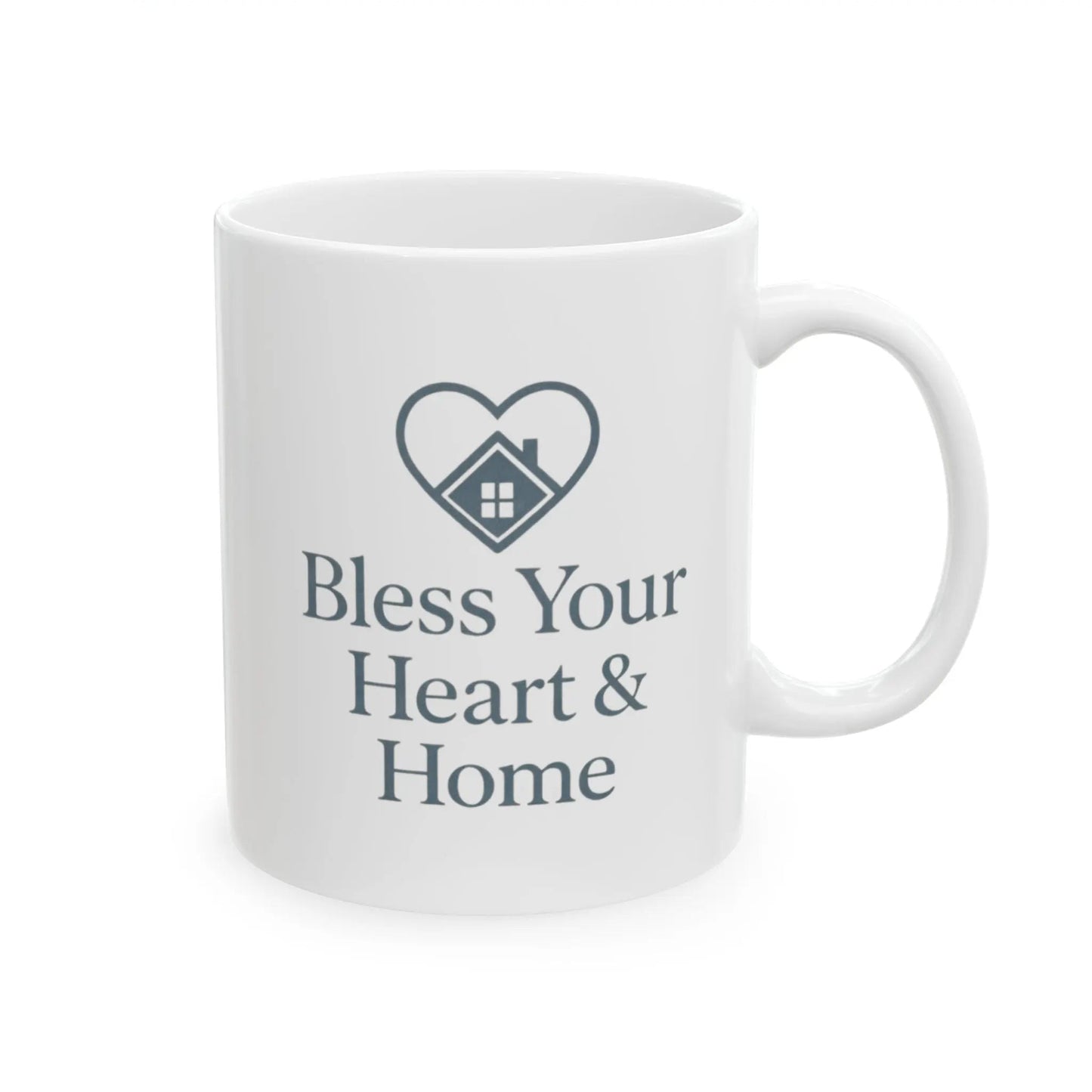 A white ceramic mug with a dark gray printed design featuring a heart outline containing a small house icon and the text 'Bless Your Heart & Home' on a clean white background.