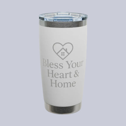 A white insulated tumbler with a clear lid and silver metal trim, featuring the text 'Bless Your Heart & Home' and a heart-shaped house graphic on the front. A small 'Comfort Colors' logo is visible in the top-left corner.