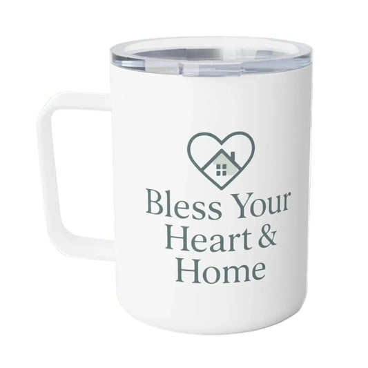 A white insulated travel mug with a clear lid, featuring a dark gray printed heart-with-house icon and the text 'Bless Your Heart & Home' on the front.