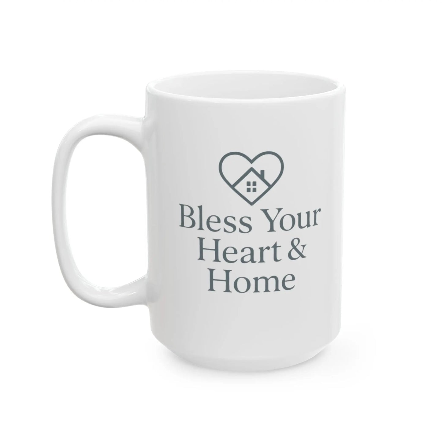 A white ceramic coffee mug with a dark gray printed design featuring a heart-shaped house icon and the text 'Bless Your Heart & Home' on a clean white background.
