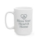 A white ceramic coffee mug with a dark gray printed design featuring a heart-shaped house icon and the text 'Bless Your Heart & Home' on a clean white background.