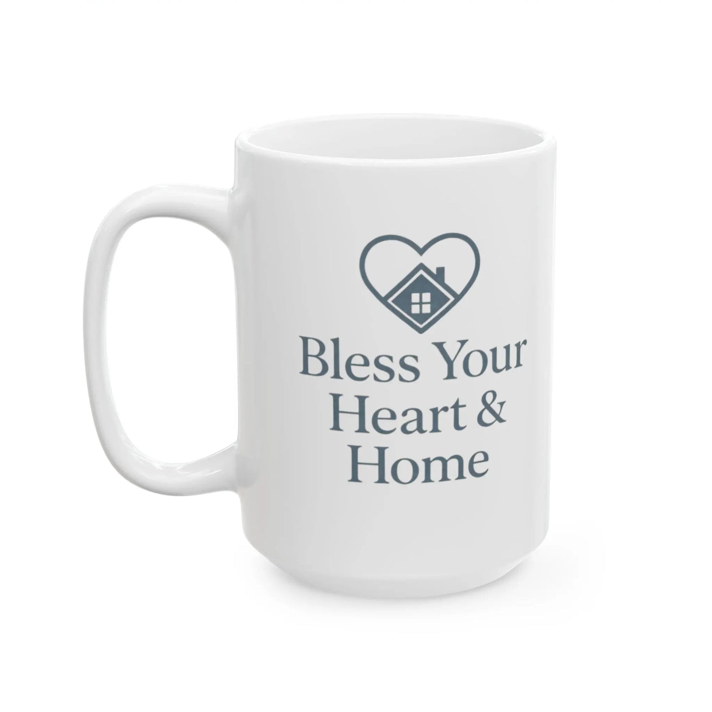 A white ceramic coffee mug with a dark gray printed design featuring a heart-shaped house icon and the text 'Bless Your Heart & Home'.