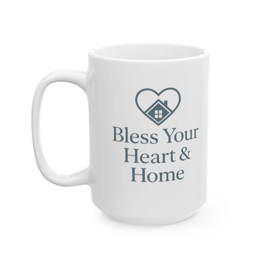 A white ceramic coffee mug with a dark gray printed design featuring a heart-shaped house icon and the text 'Bless Your Heart & Home'.
