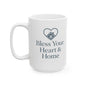 A white ceramic coffee mug with a dark gray printed design featuring a heart-shaped house icon and the text 'Bless Your Heart & Home'.