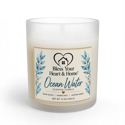 A frosted glass jar candle with a cream-colored wax and a decorative front label reading 'Ocean Water Scented Candle' by Bless Your Heart & Home, shown on a white background.