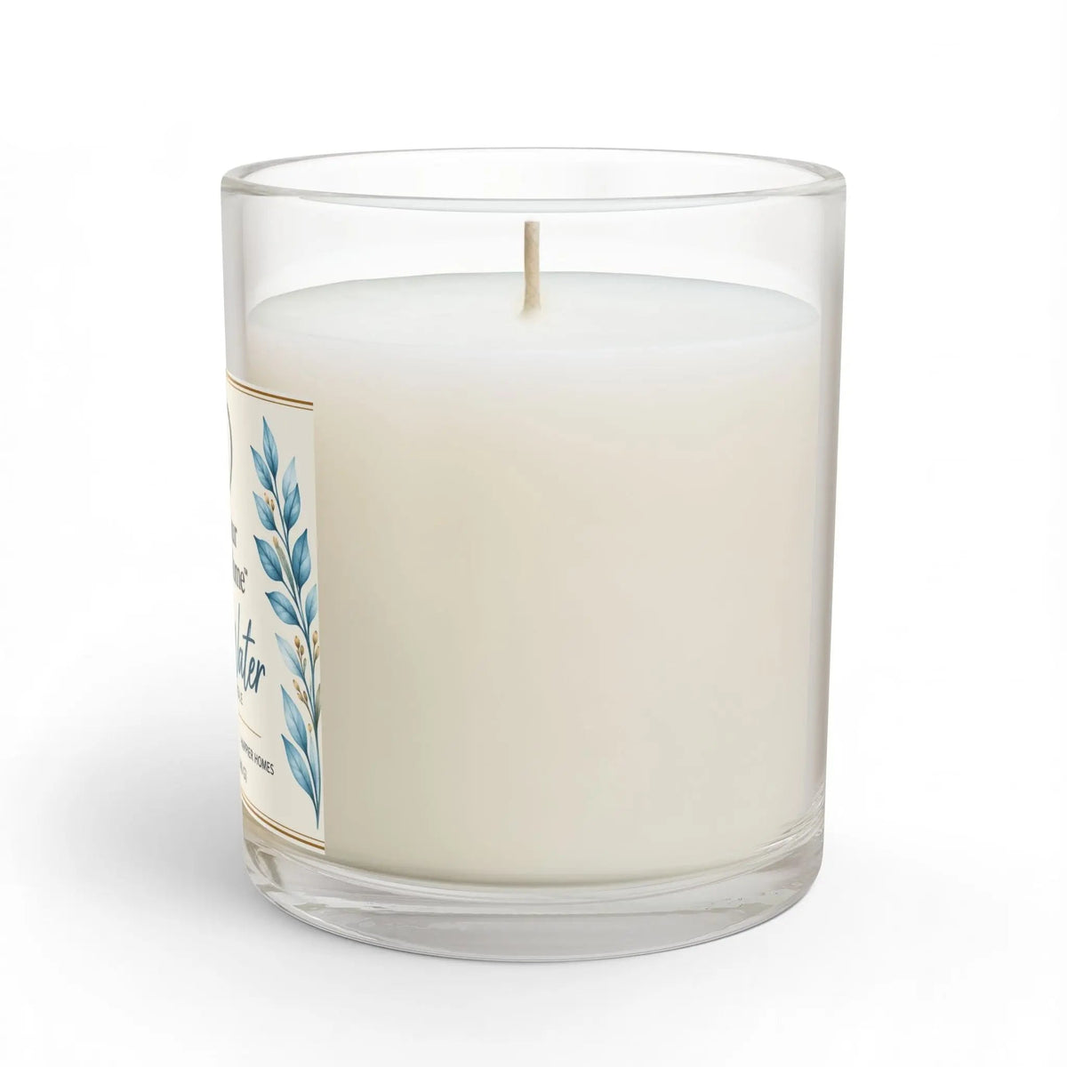 A white wax candle in a clear glass jar with a single wick, featuring a cream label with blue botanical leaf illustrations. The candle is photographed on a clean white background with a subtle shadow.