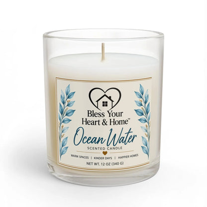 A 11 oz scented candle in a clear glass jar with a cream-colored label that reads 'Ocean Water' and features blue watercolor leaves. The candle is shown on a clean white background with a subtle shadow.