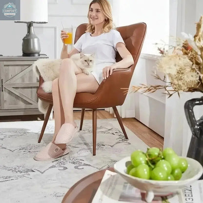 Person seated in a brown faux leather wingback accent chair demonstrating indoor seating use