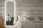 White full length LED mirror placed in bedroom showing illuminated frame and freestanding design