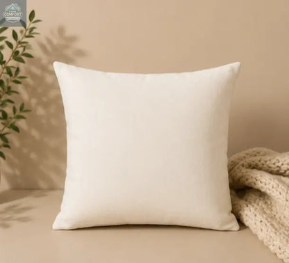 Beige pillow on a beige surface with a plant and textured fabric in the background