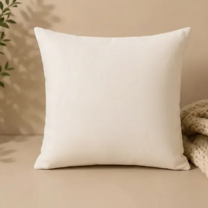Beige pillow on a beige surface with a plant and textured fabric in the background