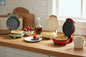 Three compact mini waffle makers in different colors displayed on a white background with one open showing cooking surface.