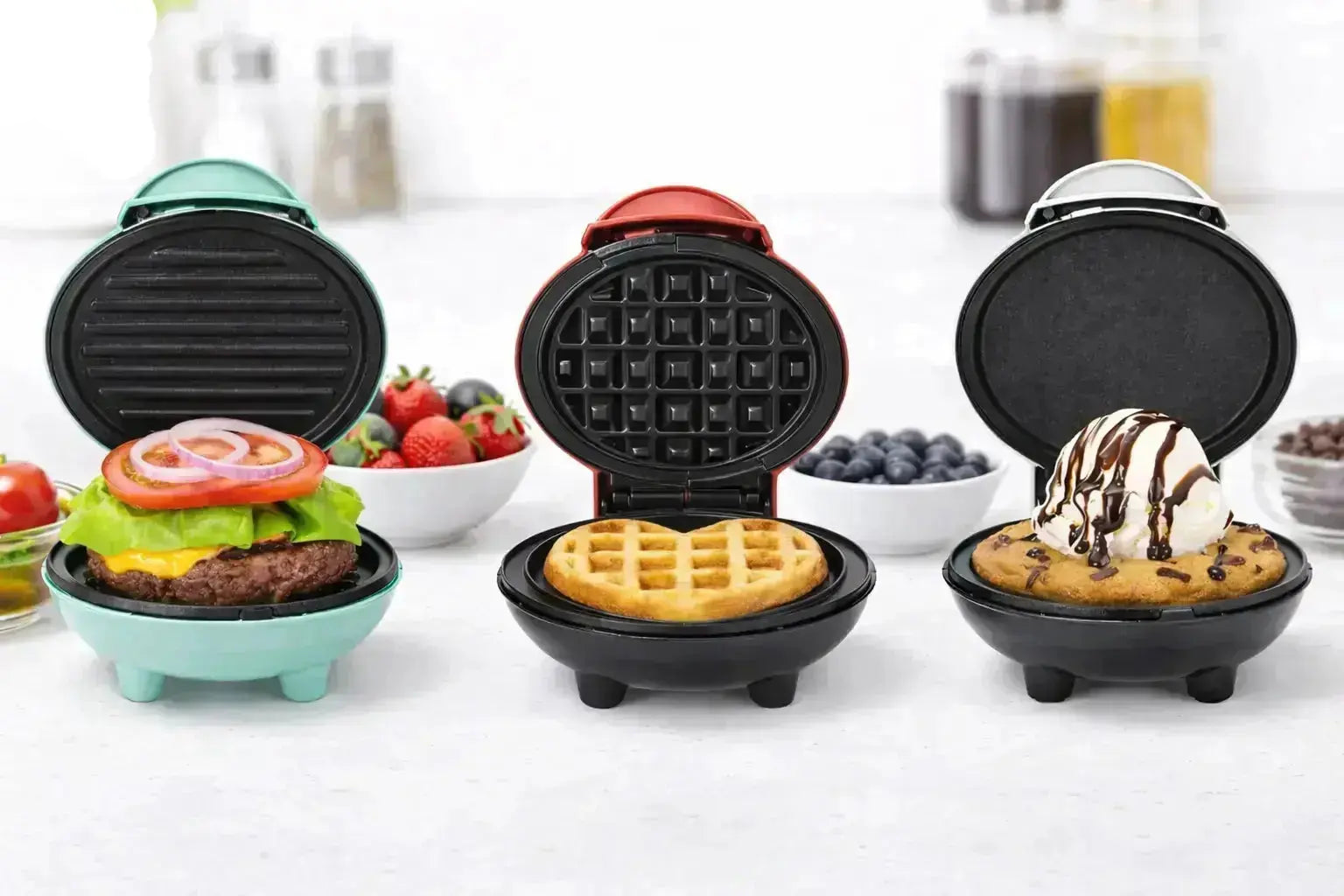 Three mini waffle makers open on a kitchen counter showing burger, waffle, and dessert cooking examples.