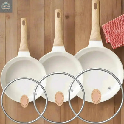 Top view of nonstick frying pan set showing three cookware sizes with glass lids and wooden handles
