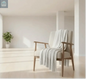 Pearl knit chenille throw blanket draped over a cozy armchair in a warm living room with fireplace