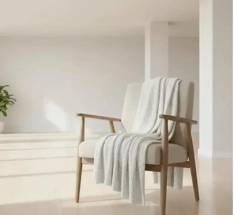 Pearl knit chenille throw blanket draped over a cozy armchair in a warm living room with fireplace