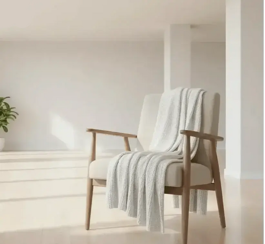 Pearl knit chenille throw blanket draped over a cozy armchair in a warm living room with fireplace